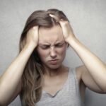Young woman expressing stress and frustration while holding her head.
